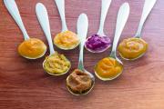 Spoons of baby food in variety of flavours