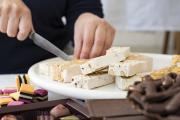 Person cutting nougat and display of sweets and chocolate