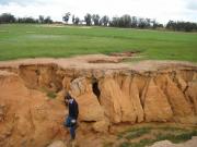 Photograph of severe gully erosion with person standing in the gully