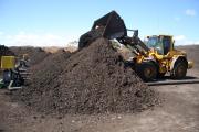 Front end loader piling partly composted material onto aeration pipes