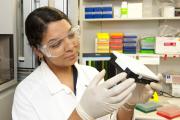 Female Grains Research officer wearing lab coat and protective eye wear looking for genetic markers (DNA) in a laboratory at Murdoch University.