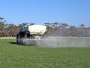 Agricultural lime being spread on a pasture in spring, a good option to spread the workload