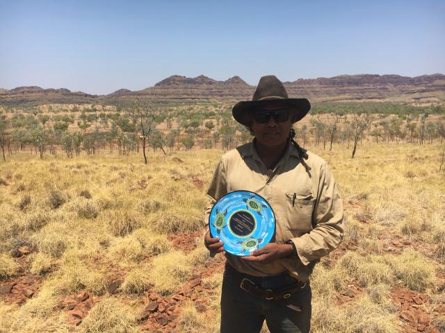 Harry Curtin with his East Kimberley Aboriginal Achievement Award Plate on a hill