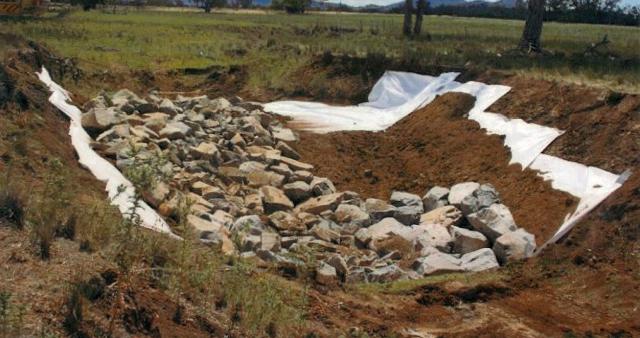 Photograph of the shaped flume with soil and rock on a geotextile lining