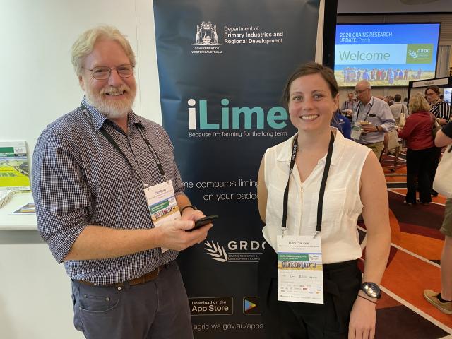 A man and woman wearing conference passes standing in front of a banner that says iLime