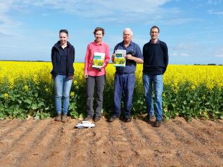 Four people standing in front of a canola crop Four people standing in front of a canola crop