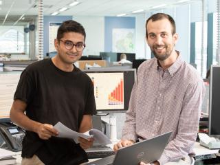 Two men in front of a computer looking at a document. Two men in front of a computer looking at a document.