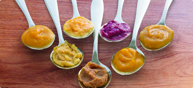 Spoons of baby food in variety of flavours