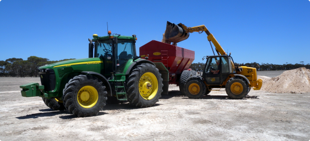 Photograph of bulk gypsum being loaded into a tractor drawn spreader for use on sodic soil