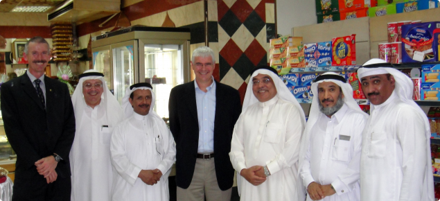 A photograph of seven men in a group facing the camera. Two dressed in western cloths and four dressed in typical Saudi dress.