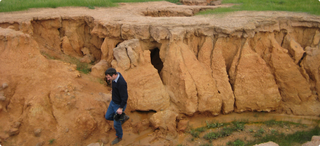 Photograph of severe gully erosion with person standing in the gully