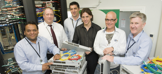 DAFWA IT infrastructure staff in server room with stack of IT network equipment.