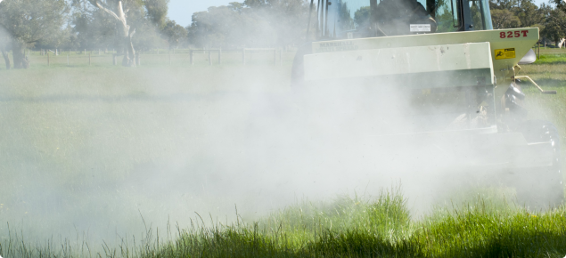 photo showing spreading of fertiliser from the back of a trailer attached to a tractor onto pasture