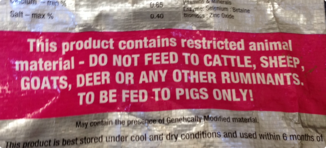 Bag of pig feed labelled with a statement indicating the feed contains restricted animal material.