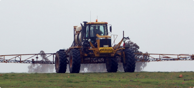 Ground rig spraying chemical onto pasture