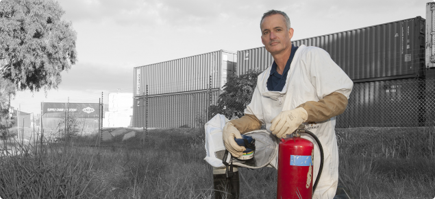 DAFWA Senior Technical Officer Marc Widmer in a protective suit, prepares to spray near shipping containers at the interstate railway terminal at Kewdale–Welshpool where many European wasp nests have been discovered.