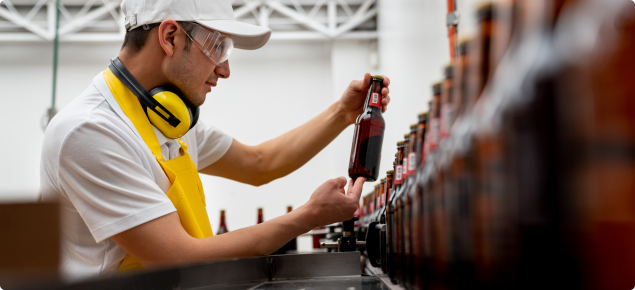 Man supervising the operation of a bottling machine at a brewery