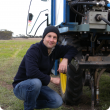 Daniel Huberli crouches near a tractor in a paddock
