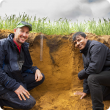 Two men examining soil in a culvit