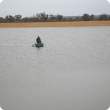 Brave DAFWA staff in a small boat measuring the depth of a large effluent pond