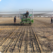 View of the back of the cone seeder as the first trial plot is seeded of the 2012 trial program.  One staff member is on the seeder while others are confirming all equipment is working properly